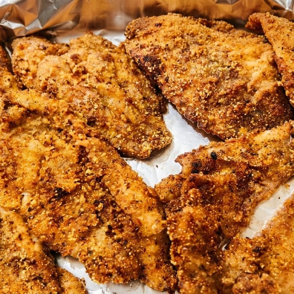 Crispy fried fish fillets in a foil-lined pan, golden brown and seasoned.