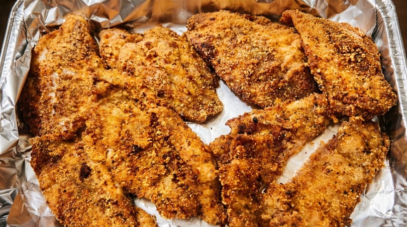 Crispy fried fish fillets in a foil-lined pan, golden brown and seasoned.